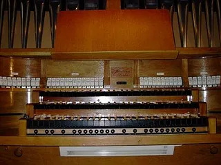 Nahaufnahme einer hölzernen Kirchenorgel mit mehreren Manualen und Pfeifen.